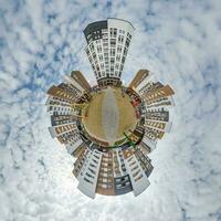 pequeño planeta en el cielo azul con nubes en el centro de la ciudad cerca de modernos rascacielos o edificios de oficinas. transformación del panorama esférico 360 en vista aérea abstracta. foto