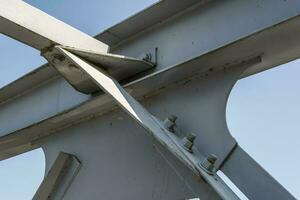 Bolts and nuts on metal plates of steel structure of heavy duty straight crossbar of frame and bridge support photo