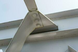 Bolts and nuts on metal plates of steel structure of heavy duty straight crossbar of frame and bridge support photo