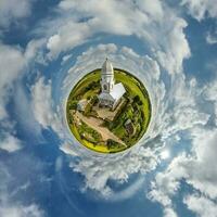 little planet transformation of spherical panorama 360 degrees overlooking church in center of globe in blue sky. Spherical abstract aerial view with curvature of space. photo