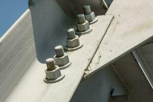 Bolts and nuts on metal plates of steel structure of heavy duty straight crossbar of frame and bridge support photo