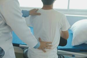 Doctor or physical therapist examines back pain and spinal area to give advice within the rehabilitation center. photo