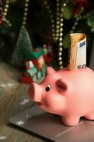 Pink piggy bank with banknote on a laptop. photo