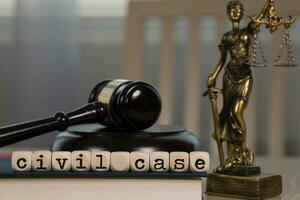 Words CIVIL CASE composed of wooden dices. Wooden gavel and statue of Themis in the background. photo