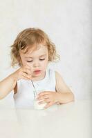 pequeño niña come natural azúcar gratis yogur. de cerca foto