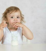 Small girl eats natural sugar free yogurt. Closeup photo