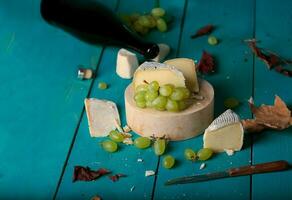 Cheese, grapes and wine on wooden cyan surface. photo