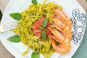 Spinach pasta with shrimps and tomato sauce photo