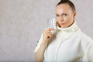 Young caucasian lady  dressed in a knitted sweater with medication. Closeup photo