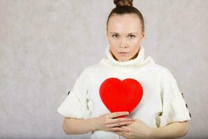 Young caucasian lady dressed in a knitted sweater with red heart box. photo