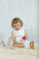 pequeño niña en un blanco vestir es jugando con su juguetes foto