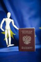 Russian pass and wooden dummy figurine on Russian and European flag. photo