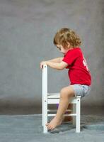 A boy and a white chair. Gray background photo