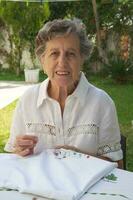 An old woman is embroidering on the white blanket photo