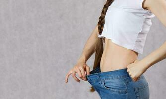 Young lady dressed in jeans lost her overweight. Closeup photo