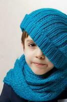 seis años antiguo niño en cian de punto bufanda y sombrero. foto