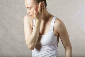 A young woman has a pain in the ear. photo