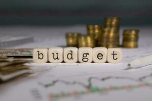 Word BUDGET composed of wooden letter. Stacks of coins in the background. photo