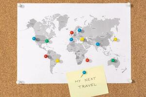 My next travel destination concept. Pushpins on world map on Corkboard and yellow sticky note photo