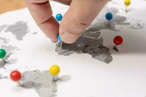 Close up of Human Hand pinning on world map. Travel destination concept photo