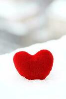 Red plush heart in the snow. photo