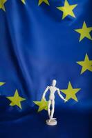 Wooden dummy figurine on European flag. photo