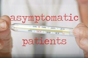 Words ASYMPTOMATIC PATIENTS. Senior woman keeps thermometer in the background photo