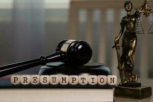 Word PRESUMPTION composed of wooden dices. Wooden gavel and statue of Themis in the background. photo