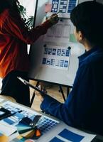 Close up ux developer and ui designer brainstorming about mobile app interface wireframe design on table with customer breif and color code at modern office.Creative digital development agency photo