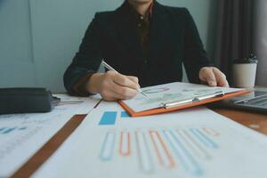 Group of confident business people point to graphs and charts to analyze market data, balance sheet, account, net profit to plan new sales strategies to increase production capacity. photo