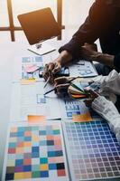 Close up ux developer and ui designer brainstorming about mobile app interface wireframe design on table with customer breif and color code at modern office.Creative digital development agency photo