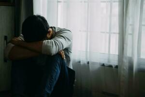 Alone man silhouette staring at the window closed with curtains in bedroom. Man stands at window alone photo