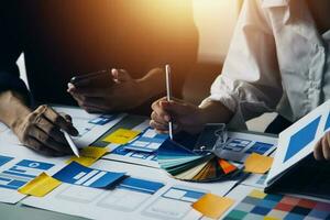 Close up ux developer and ui designer brainstorming about mobile app interface wireframe design on table with customer breif and color code at modern office.Creative digital development agency photo