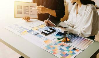 Close up ux developer and ui designer brainstorming about mobile app interface wireframe design on table with customer breif and color code at modern office.Creative digital development agency photo