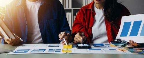 Close up ux developer and ui designer brainstorming about mobile app interface wireframe design on table with customer breif and color code at modern office.Creative digital development agency photo