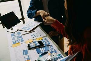 Close up ux developer and ui designer brainstorming about mobile app interface wireframe design on table with customer breif and color code at modern office.Creative digital development agency photo