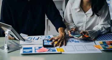 Close up ux developer and ui designer brainstorming about mobile app interface wireframe design on table with customer breif and color code at modern office.Creative digital development agency photo