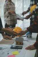 reunión de trabajo en equipo de ingenieros, trabajo de dibujo en la reunión de planos para el trabajo del proyecto con un socio en la construcción de modelos y herramientas de ingeniería en el concepto de sitio de trabajo, construcción y estructura. foto