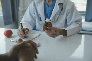 médico y paciente que se discute Actual salud examen mientras sentado a el escritorio en clínica oficina, de cerca. medicina concepto. foto