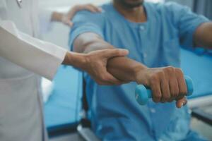 Physiotherapist man giving exercise with dumbbell treatment About Arm and Shoulder of athlete male patient Physical therapy concept photo