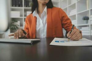 Asian Business woman using calculator and laptop for doing math finance on an office desk, tax, report, accounting, statistics, and analytical research concept photo