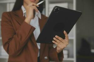 Asian Business woman using calculator and laptop for doing math finance on an office desk, tax, report, accounting, statistics, and analytical research concept photo
