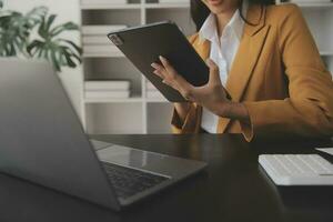 Asian Business woman using calculator and laptop for doing math finance on an office desk, tax, report, accounting, statistics, and analytical research concept photo