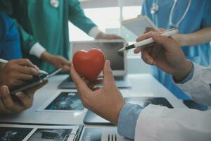 multirracial equipo de doctores que se discute un paciente en pie agrupado en el vestíbulo mirando a un tableta computadora, cerca arriba ver foto