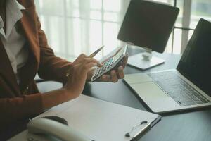 Close up Business woman using calculator and laptop for do math finance on wooden desk, tax, accounting, statistics and analytical research concept photo