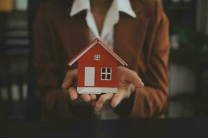 Female woman hands holding home model, small miniature white toy house. Mortgage property insurance dream moving home and real estate concept photo