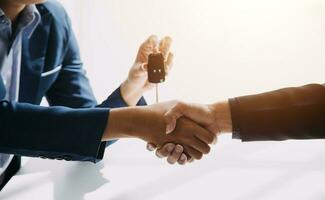 A car rental company employee is handing out the car keys to the renter after discussing the rental details and conditions together with the renter signing a car rental agreement. Concept car rental. photo