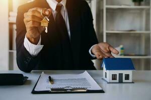 Accountant, businessman, real estate agent, Asian business woman handing keys to customers along with house after customers to sign photo