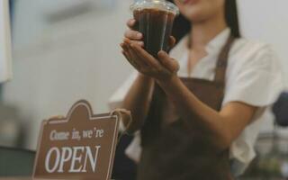 Young entrepreneur holding open sign on glass door at cafe photo