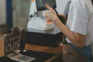 Young entrepreneur holding open sign on glass door at cafe photo